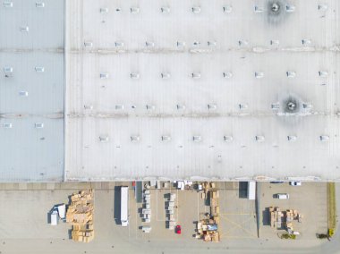 Malzeme deposunun havadan görüntüsü. Sanayi bölgesindeki lojistik merkezi yukarıdan. Lojistik merkezde yüklenen kamyonların hava görüntüsü. İnsansız hava aracından görüntüle.