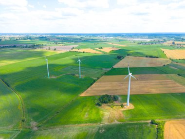 Yükseklerdeki bulutlu gökyüzünde enerji üretimi için güçlü rüzgar türbini çiftliğinin hava manzarası. Rüzgar güç türbinleri sürdürülebilir kalkınma için temiz yenilenebilir enerji üretiyor.
