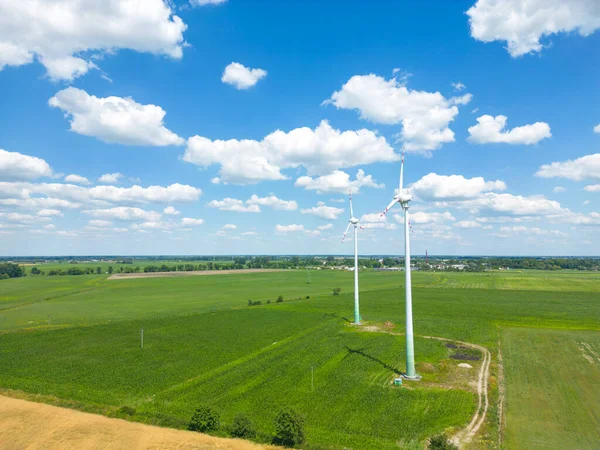 Aerial drone view of wind power turbines, part of a wind farm. Wind turbines on green field in countryside. Wind power plant.