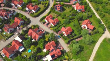 Gün batımında mahalle ve apartman kompleksinin havadan görüntüsü. Sıkışık evler, garaj yolu yeşil ağaç üstgeçidini çevreleyen Suburban konutları