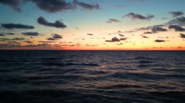 Okyanus suyunun üzerinde tropik altın gün batımı yavaş çekim hava manzarası. Güneş deniz manzarasına yansıyor. Sea Bay 'de kimsenin olmadığı bir kumsal. Güneşli bir akşamda sakin bir su manzarası. Yaz tatili. Tropik tatil