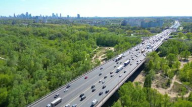 Hava takibi, birden fazla yol ayrımını yükseltti. Güneşli bir akşamda İHA görüntüsü şehir karayolu kavşağında. Kavşak otoyolu üst geçidi. Arabayı takip et. Yaz günü, yeşil ağaçlar çimenler