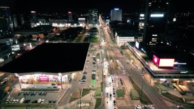 Gece şehir yollarının tepesinde hava manzaralı arabalar var. Geceleri modern gökdelenleri olan şehir manzarası. Görkemli şehir manzarası trafik otobanlı neon fenerlerle aydınlatılıyor. Sinematik araç manzarası