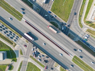 Otoyol kavşağı kavşağının hava manzarası. Yükseltilmiş yolun, trafik kavşaklarının ve yeşil bahçenin drone görüntüsü. Otoyolda giden nakliye kamyonları ve arabalar. Modern şehirde altyapı.