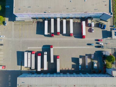 Depoyla birlikte lojistik parkı. Yarı karavan kamyonları araba parkında duruyor ve yükleme ve boşaltma için rampalarda bekliyorlar. Hava görünümü