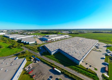 Gün batımında yükleme / boşaltma malları için rampalarda bekleyen depo, merkez ve kargo karavanıyla lojistik parkının hava görüntüsü.