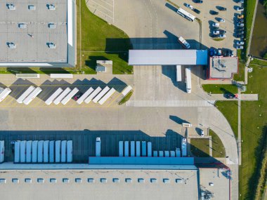 Gün batımında yükleme / boşaltma malları için rampalarda bekleyen depo, merkez ve kargo karavanıyla lojistik parkının hava görüntüsü.