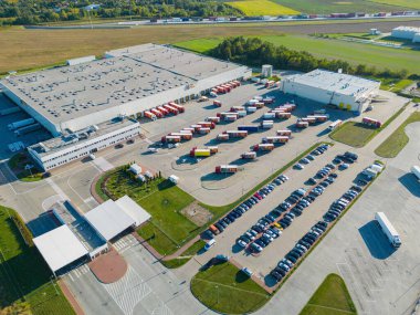 Gün batımında yükleme / boşaltma malları için rampalarda bekleyen depo, merkez ve kargo karavanıyla lojistik parkının hava görüntüsü.