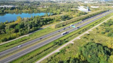 Otobanın havadan görünüşü. Yükseltilmiş yolun, trafik kavşaklarının ve yeşil bahçenin drone görüntüsü. Otoyolda giden nakliye kamyonları ve arabalar. Modern şehirde altyapı.