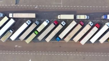 Aerial Shot of Truck with Attached Semi Trailer Leaving Industrial Warehouse/ Storage Building/ Loading Area where Many Trucks Are Loading/ Unloading Merchandise. Shot on Phantom 4K UHD Camera.