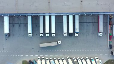 Depo rampalarında durmakta olan kargo römorklu bir tırın hava görüntüsü. Yükleme merkezli büyük lojistik parkındaki malları yüklemek / boşaltmak için.