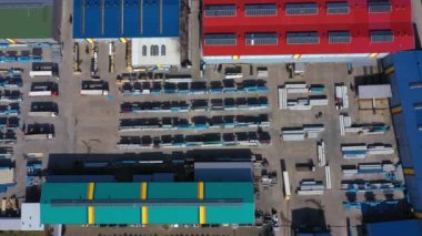 Aerial view of a semi trucks with cargo trailers standing on warehouses ramps for loading/unloading goods on the big logistics park with loading hub