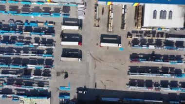 Kargo karavanlı yarı kamyon bir lojistik parkının deposu boyunca bir otoparkta seyahat ediyor. Aşağıdaki hava çekimi