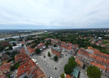 Huzurlu bir nehrin kıyısında uzanan antik Sandomierz kasabasının nefes kesici güzelliğini deneyimleyin. Güneşle öpülmüş mimarinin sıcak tonları..