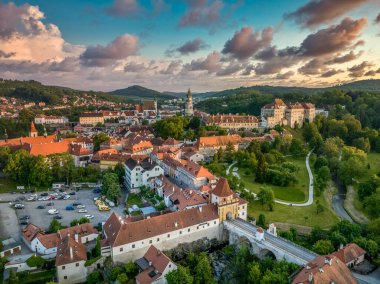 Cesky Krumlov 'un Vltava nehri boyunca St. Jost kilisesi, ortaçağ şatosu ve kırmızı çatılı evleri, çarpıcı renkli dramatik günbatımı gökyüzü