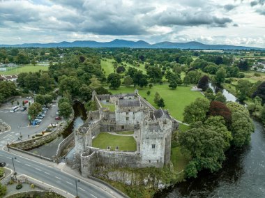İrlanda 'daki Cahir şatosu ve kasabasının havadan görünüşü. Kule Kulesi, dış kale, dairesel, dikdörtgen kuleler, banket salonu, Suir Nehri' ndeki geçişi koruyan şelale ve golf sahası.