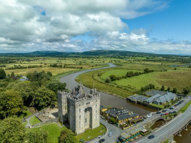 Bunratty Kalesi 'nin havadan görünüşü İrlanda' nın Clare ilçesindeki 15. yüzyıldan kalma büyük bir kule evi Ralty nehrinin geçidini Shannon nehrine ulaşmadan koruyor.