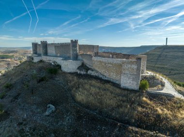 İspanya 'nın Guadalajara eyaletindeki Jadraque ortaçağ tepe şatosunun Henares nehrinin yukarısındaki Henares Nehri' nin üzerinde, jet akıntıları ile mavi gökyüzü.