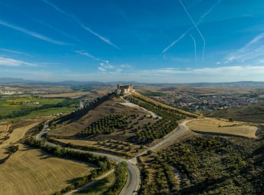 İspanya 'nın Guadalajara eyaletindeki Jadraque ortaçağ tepe şatosunun Henares nehrinin yukarısındaki Henares Nehri' nin üzerinde, jet akıntıları ile mavi gökyüzü.