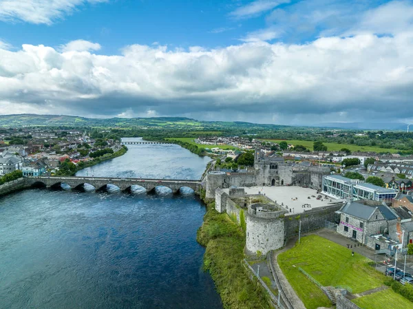 Limerick şehrinin ve Kral John 'un kalesinin Shannon nehri ve Thomond köprüsü boyunca eşmerkezli duvarları ve yuvarlak kuleleri olan havadan görüntüsü.