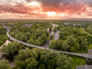 Canlı Köprü 'nün havadan panoramik görüntüsü, günbatımının çarpıcı olduğu Limerick Üniversitesi' ndeki Shannon Nehri 'nden geçen modern yayaları eğerek...