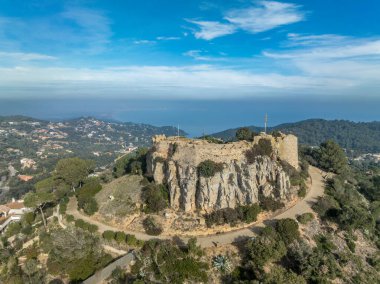 Aerial view of 16th-century Begur castle fort atop a forested hill, with panoramic views of the Mediterranean Sea. Watch towers built against the pirates clipart