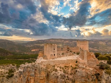 Cortes de Pallas 'taki el Jugar geçidinde bulunan kayalık bir kayanın tepesindeki havadan panoramik manzara, üçgen yerleşim alanı, ok yarıkları, korkuluklar, moa, su tankı, ana kule, dramatik gökyüzü.