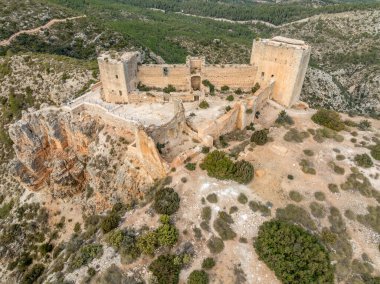 Cortes de Pallas 'taki el Jugar geçidinde bulunan kayalık bir kayanın tepesindeki havadan panoramik manzara, üçgen yerleşim alanı, ok yarıkları, korkuluklar, moa, su tankı, ana kule, dramatik gökyüzü.