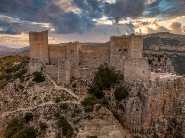 Cortes de Pallas 'taki el Jugar geçidinde bulunan kayalık bir kayanın tepesindeki havadan panoramik manzara, üçgen yerleşim alanı, ok yarıkları, korkuluklar, moa, su tankı, ana kule, dramatik gökyüzü.
