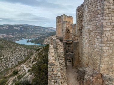 Cortes de Pallas 'taki el Jugar geçidinde bulunan kayalık bir kayanın tepesindeki havadan panoramik manzara, üçgen yerleşim alanı, ok yarıkları, korkuluklar, moa, su tankı, ana kule, dramatik gökyüzü.