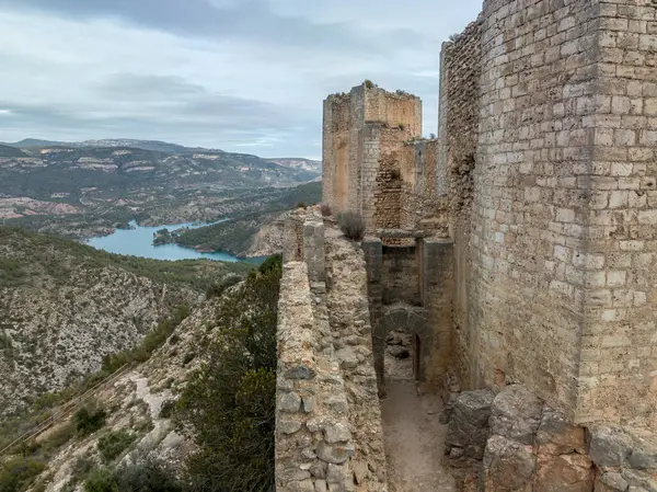 Cortes de Pallas 'taki el Jugar geçidinde bulunan kayalık bir kayanın tepesindeki havadan panoramik manzara, üçgen yerleşim alanı, ok yarıkları, korkuluklar, moa, su tankı, ana kule, dramatik gökyüzü.