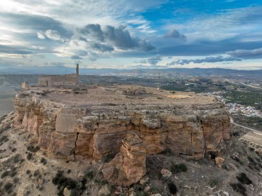 Castillo de Alcal ya da Castillo de La Puebla 'nın havadan görünüşü Murcia' nın düz kireçtaşı dağının tepesindeki Arap kalesi. Büyük dikdörtgen kule, açılı giriş, derin kuyu ve kazılmış toprak ve enkazdan yapılmış sarnıç.