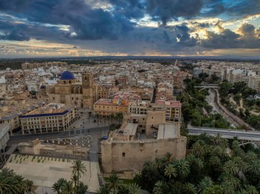 Elche 'nin (Elx) tarihi merkezi, Altamira Ortaçağ Şatosu Ulusal Anıtı, palmiye ağaçları dramatik günbatımı gökyüzü