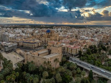 Elche 'nin (Elx) tarihi merkezi, Altamira Ortaçağ Şatosu Ulusal Anıtı, palmiye ağaçları dramatik günbatımı gökyüzü