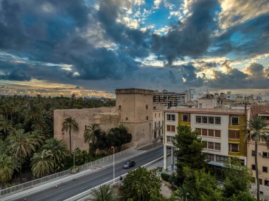 Elche 'nin (Elx) tarihi merkezi, Altamira Ortaçağ Şatosu Ulusal Anıtı, palmiye ağaçları dramatik günbatımı gökyüzü
