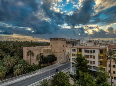 Aerial view of Elche (Elx) historic center, Altamira medieval castle national monument, palm trees dramatic sunset sky clipart