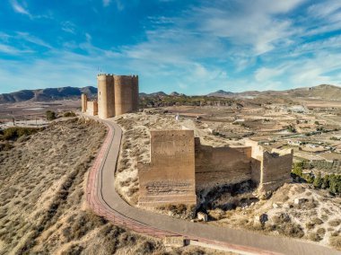 Murcia İspanya 'daki Jumilla ortaçağ şatosunun havadan görünüşü, bir tepe üzerinde, düzensiz şekiller, dört katlı, yarılmış siperler bulutlu mavi gökyüzü arkaplanı