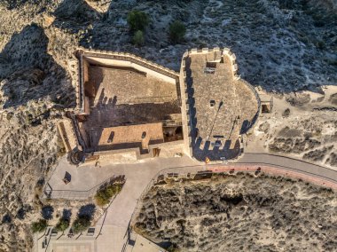Murcia İspanya 'daki Jumilla ortaçağ şatosunun havadan görünüşü, bir tepe üzerinde, düzensiz şekiller, dört katlı, yarılmış siperler bulutlu mavi gökyüzü arkaplanı