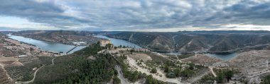 Mequinenza 'nın Mequinenza Barajı ile Riba-roja rezervuarı arasında Ebro' nun kavşağındaki hava manzarası. Stratejik konumdaki açılı kalelerle güçlendirme, dramatik gökyüzü