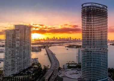 Renkli günbatımı gökyüzü ile Miami ufuk çizgisi, MacArthur geçidi Florida 'daki iki yeni emlak geliştirme lüks apartmanı arasında geçiyor.