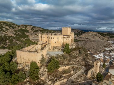 Velez Blanco Kalesi 'nin tepedeki ve kasabadaki havadan görünüşü. Bir ya da iki katlı evler, beyazlatılmış duvarlar ve Endülüs İspanya' sında dramatik bulutlu bir gökyüzü ile döşeli çatılar.