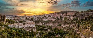 La Mancha İspanya 'daki Cuenca tarihi şehir merkezinde günbatımı, kayalıklarda çarpıcı renkli gökyüzü olan ortaçağ evleri