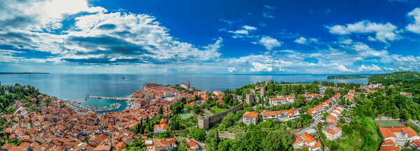 Aerial view of Piran medieval old town in Istria Slovenia with red rooftops, city wall, catholic church, popular tourist destination