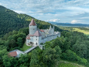 Zovnek kalesinin hava panoramik manzarası, Slovenya 'nın en eski ortaçağ kalesi kısmen restore edilmiş büyük kulesi, kale kapısı, köprü