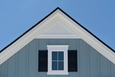 Beyaz çerçeveli tavan arası menfezi mavi kaplamalı, gable, corbel, daha yüksek sesli Doğu Sahili 'ndeki lüks bir Amerikan aile evi mavi gökyüzü arka planına sahip.