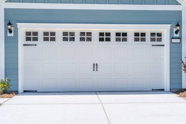 Çift araba klasik yalıtılmış çelik kapaklı beyaz garaj kapısı aksan eklemek için çerçevelenmiş, Transom light pencereler Muntin ile bölünmüş yeni bir Amerikan evi.