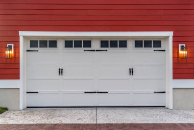 Beyaz elektronik garaj kapıları çift katlı garaj yolunda ışık pencereleri kırmızı yatay kaplamalı, siyah toz kaplı çelik kemer menteşeli. 
