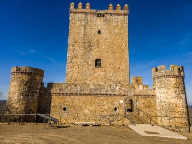 Aerial view of Nogales castle in Spain with homage tower, battlements and 4 circular towers on a hilltop clipart