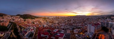 Aerial view of Malaga town center, el ejido, San Felipe Neri, La Goleta Ventaja Alta neighborhoods, Gibralfaro castle dramatic colorful sunset sky clipart