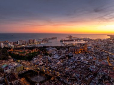 Aerial view of Malaga town center, el ejido, San Felipe Neri, La Goleta Ventaja Alta neighborhoods, Gibralfaro castle dramatic colorful sunset sky clipart